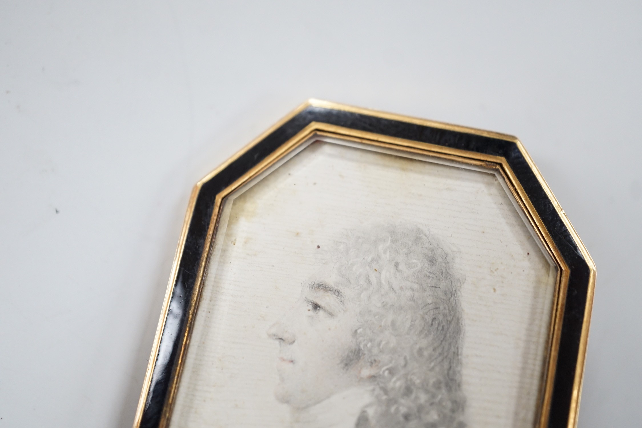 A Regency yellow metal and black enamel framed brooch (pin missing), with inset miniature pencil portrait of a bust of a gentleman to dexter, 51mm.